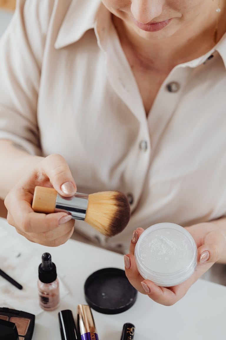Close-up of woman using makeup brush with loose powder.