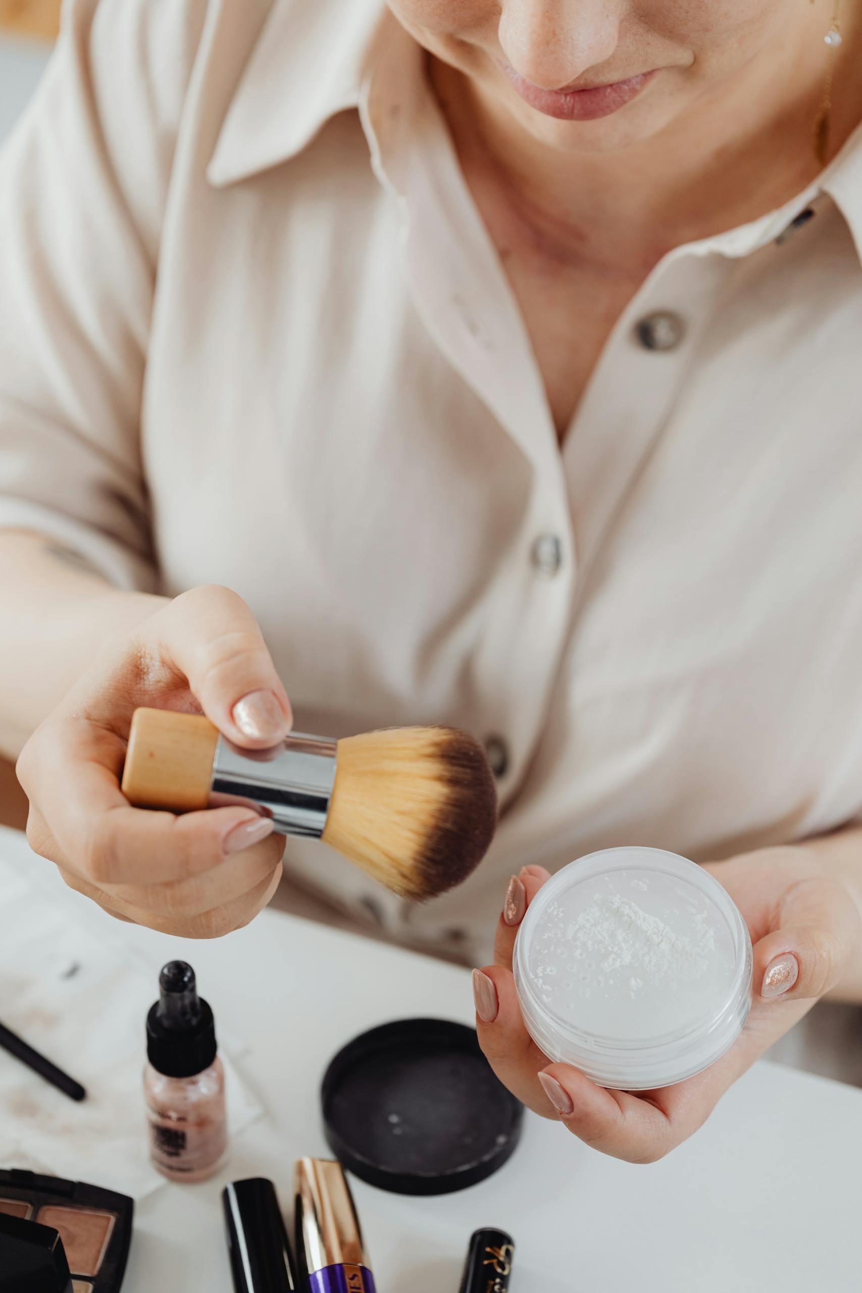Close-up of woman using makeup brush with loose powder.